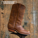Palouse western boot sitting on boot jack in front of wooden backdrop. Top left reads 'LEATHER: PREDATOR ORANGE/ SHRUNKEN BISON BROWN'.