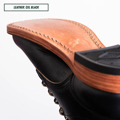 Close-up of the heel and sole of a black lace-up boot, showing a tan leather footbed and a black outsole. A text label in the top left reads 'LEATHER: CXL BLACK'.