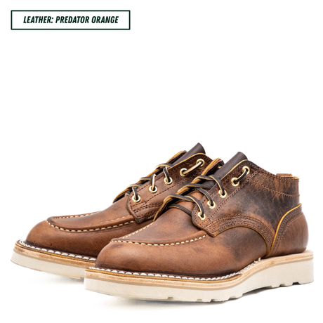 A pair of distressed brown leather lace-up shoes with tan stitching and off-white soles, shown on a white background with a text label in the top left that reads 'LEATHER: PREDATOR ORANGE'.