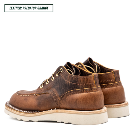 A pair of distressed brown leather lace-up boots with a thick off-white sole, shown from a three-quarters angle on a white background. A text label in the top-left corner reads 'LEATHER: PREDATOR ORANGE'.