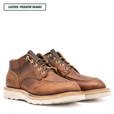 A pair of low-top lace-up boots in distressed brown leather, labeled 'LEATHER: PREDATOR ORANGE' in the top-left corner. The boots feature a rich brown leather upper with gold-toned eyelets and laces, contrast stitching, and a thick off-white rubber sole.