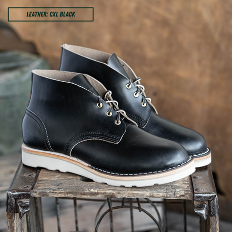 Black leather boots sitting on crate. A text box in the top left corner reads 'LEATHER: CXL BLACK'.