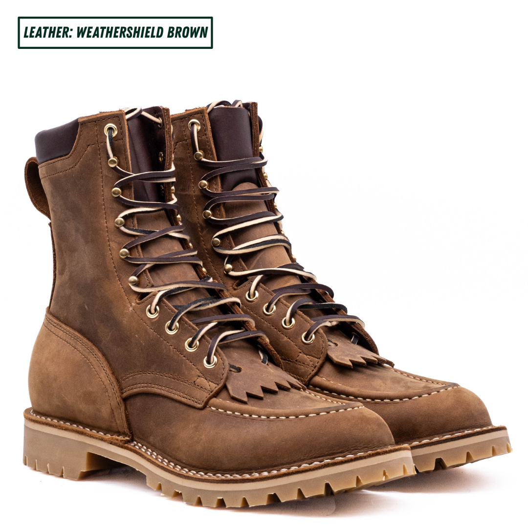 A pair of rugged lace-up work boots in a textured brown leather, shown from a three-quarters angle on a white background. A text label in the top-left corner reads 'LEATHER: WEATHERSHIELD BROWN'.