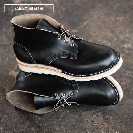 Black leather boots sitting on textured concrete. A text box in the top left corner reads 'LEATHER: CXL BLACK'.