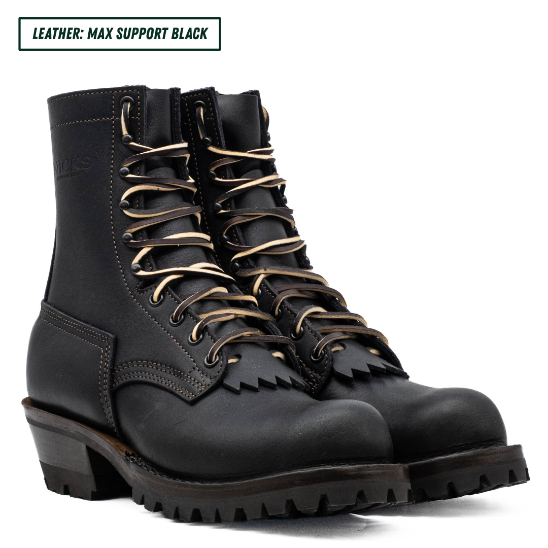 A black leather lace-up work boot shown in profile against a white background, with a text label in the top-left corner reading 'LEATHER: MAX SUPPORT BLACK'. The boot features a rugged lug sole, a stacked heel, and metal eyelets.