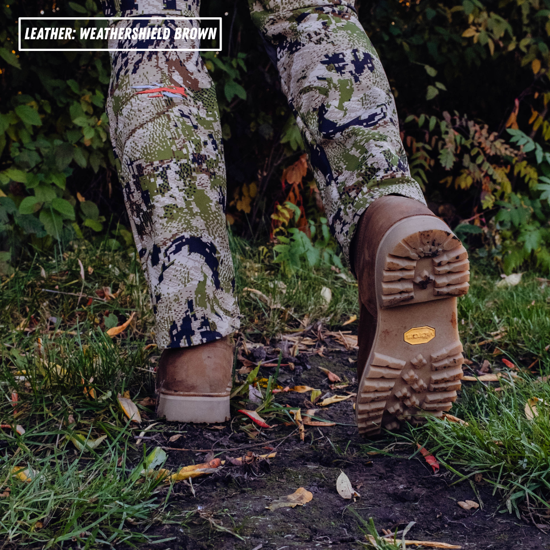 Model walking through grass, wearing camo pants and brown leather boots. Honey vibram outsole is shown. Top left reads 'LEATHER: WEATHERSHIELD BROWN'.