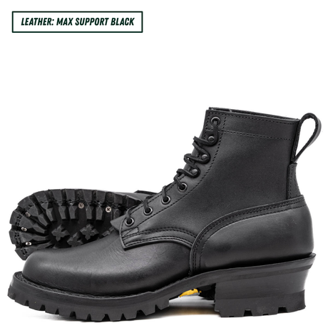 A pair of black leather lace-up boots with rugged lug soles, shown on a white background. One boot is positioned upright in profile, and the other lies behind it showing the treaded outsole.