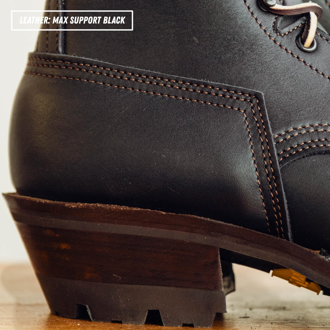 Close-up of a black leather lace-up boot heel and sole, showing dark brown stitching and a dark brown stacked heel. Text overlay in the top left reads 'LEATHER: MAX SUPPORT BLACK'.