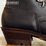 Close-up of a black leather lace-up boot heel and sole, showing dark brown stitching and a dark brown stacked heel. Text overlay in the top left reads 'LEATHER: MAX SUPPORT BLACK'.