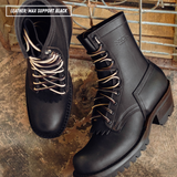 A pair of black leather lace-up ankle boots with fringed detailing and chunky lug soles, displayed on a rustic textured surface with a wooden crate in the background. A text overlay in the top left reads 'LEATHER: MAX SUPPORT BLACK'.
