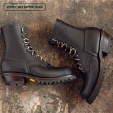 A pair of black leather lace-up boots arranged on a distressed brown textured surface. One boot is shown in profile with its laces threaded through metal eyelets, and the other is angled to show the side and heel.