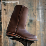 A brown leather cowboy boot shown in profile on a metal boot jack against a rustic wooden plank background. A text overlay in the top-left corner reads 'LEATHER: 1964 BROWN'.