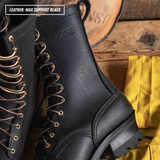 A close-up of a black leather lace-up boot with metal eyelets, shown alongside another boot and a yellow cloth on a rustic wooden surface. Text in the top-left corner reads 'LEATHER: MAX SUPPORT BLACK' and the embossed brand 'NICKS' is visible on the side of the boot.
