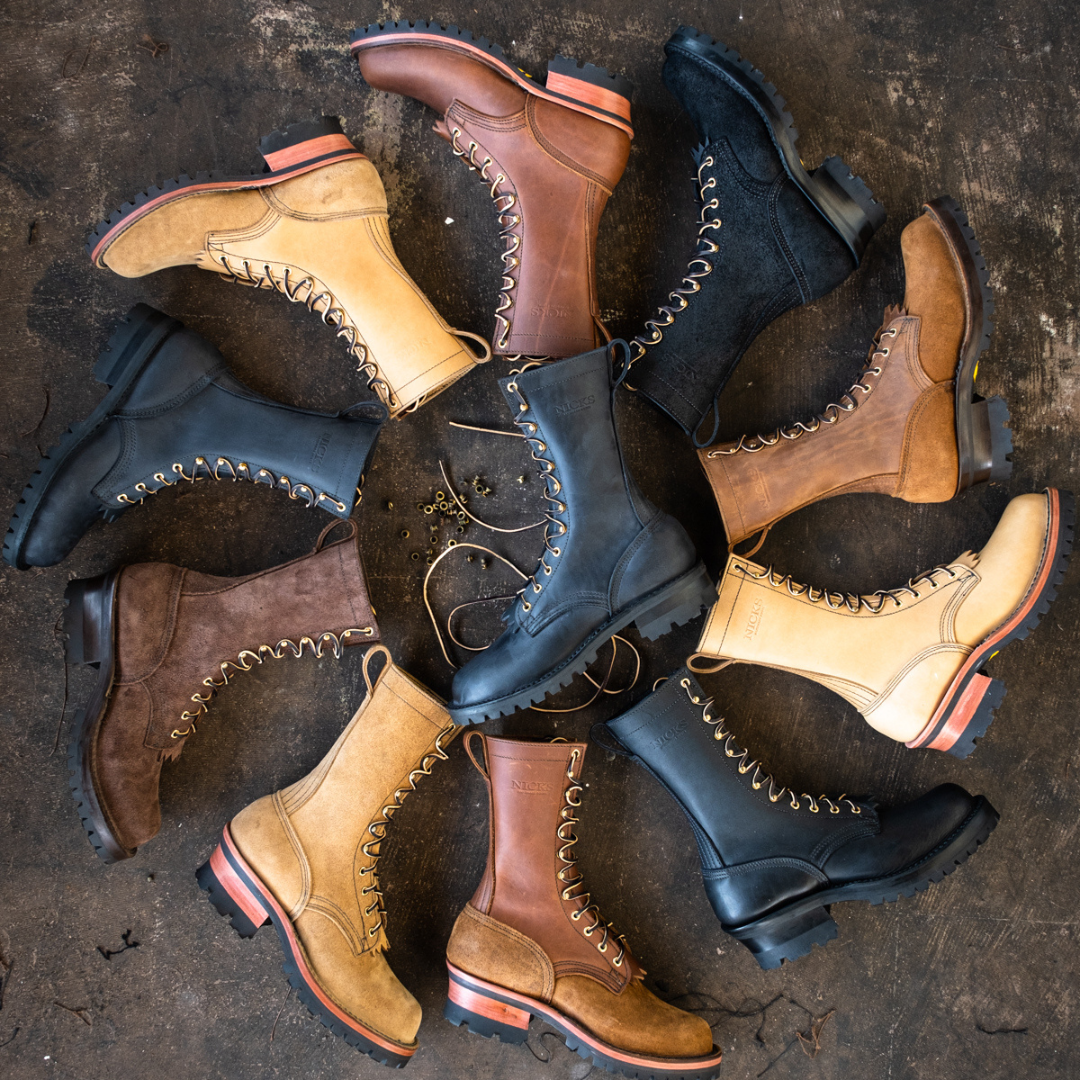 A circular arrangement of multiple lace-up work boots in black, brown, and tan suede, photographed from above on a dark textured concrete surface.