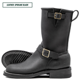 A pair of black leather mid-calf boots with gold-tone buckle straps, shown on a white background with one boot standing upright and the other lying flat to display the sole.
