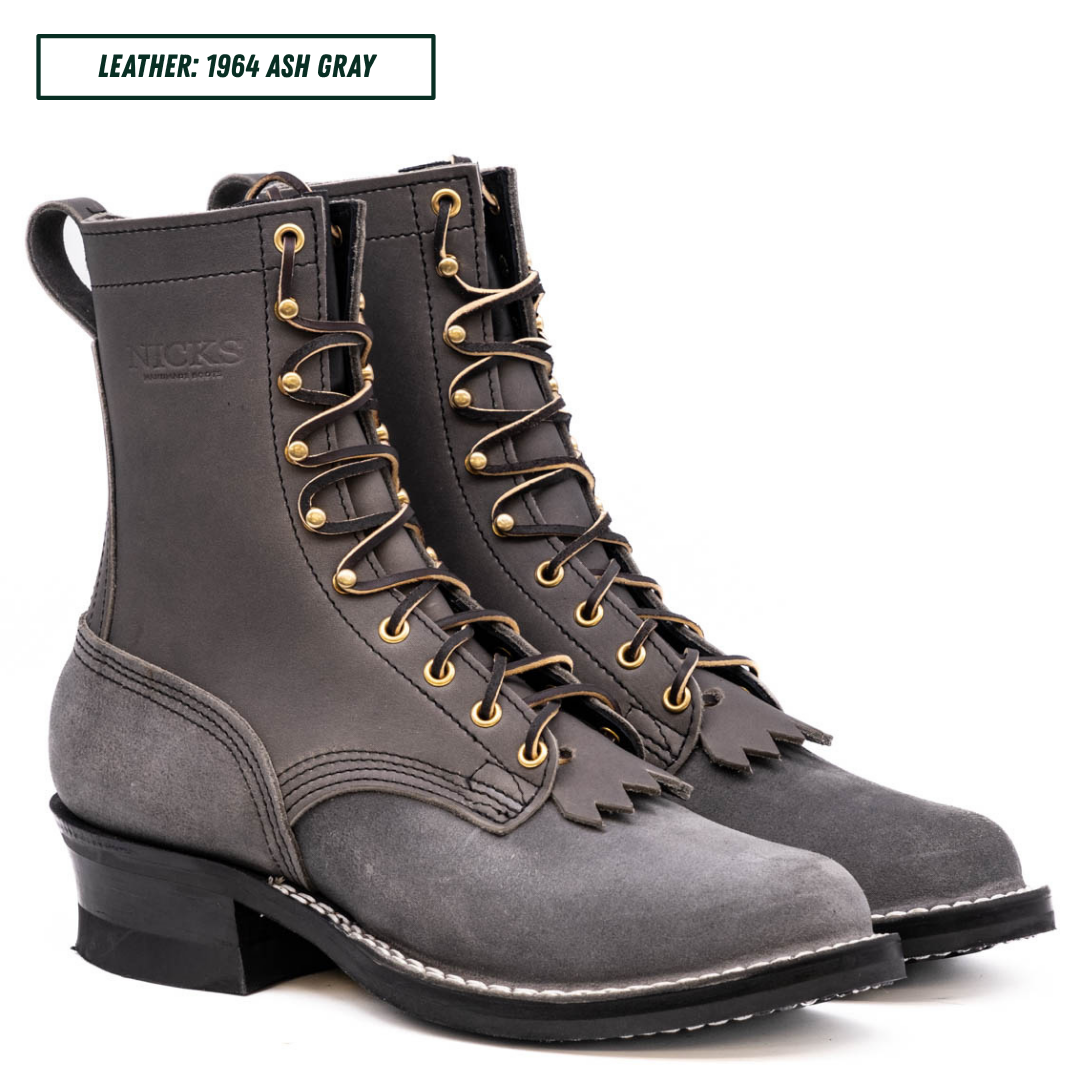A pair of dark gray leather lace-up boots with gold-tone eyelets and laces, shown on a white background with a text label at the top reading 'LEATHER: 1964 ASH GRAY'.