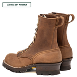 A pair of brown suede lace-up ankle boots with dark brown lug soles and pull tabs, shown on a white background with a text label in the top left reading 'LEATHER: 1964 MONARCH'.