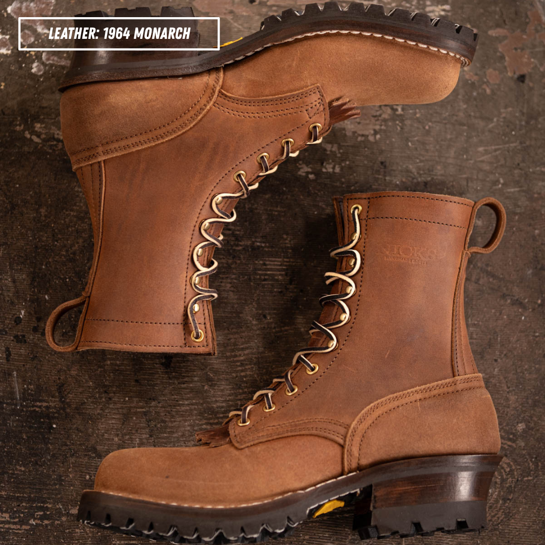 A pair of brown leather lace-up boots with dark soles and brass eyelets, arranged on a rustic dark wood background. A text overlay in the top left reads 'LEATHER: 1964 MONARCH'.