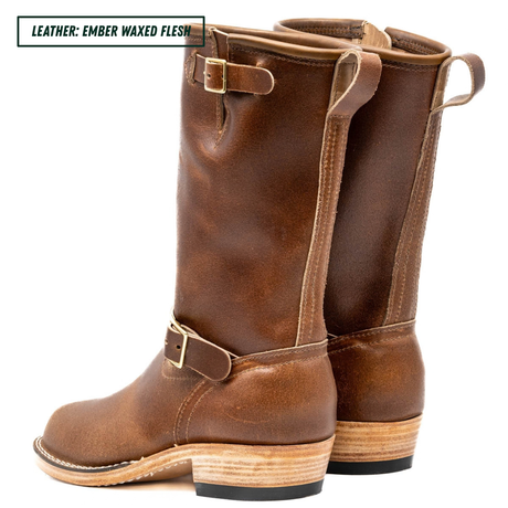 A pair of mid-calf leather boots in a warm brown shade, featuring a stacked wood-look heel and brass buckle details, shown against a plain white background with a text label in the top left corner.