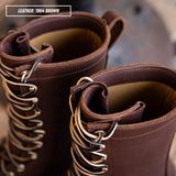 Close-up of a pair of lace-up boots in dark brown leather with silver metal eyelets and laces, showing the interior lining and collar detail. A text label in the top left reads 'LEATHER: 1964 BROWN'.