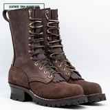 A pair of high-top brown leather lace-up boots with gold-toned metal eyelets and a chunky black lug sole, shown on a white studio background. A text label in the top-left corner reads 'LEATHER: 1964 MAHOGANY'.