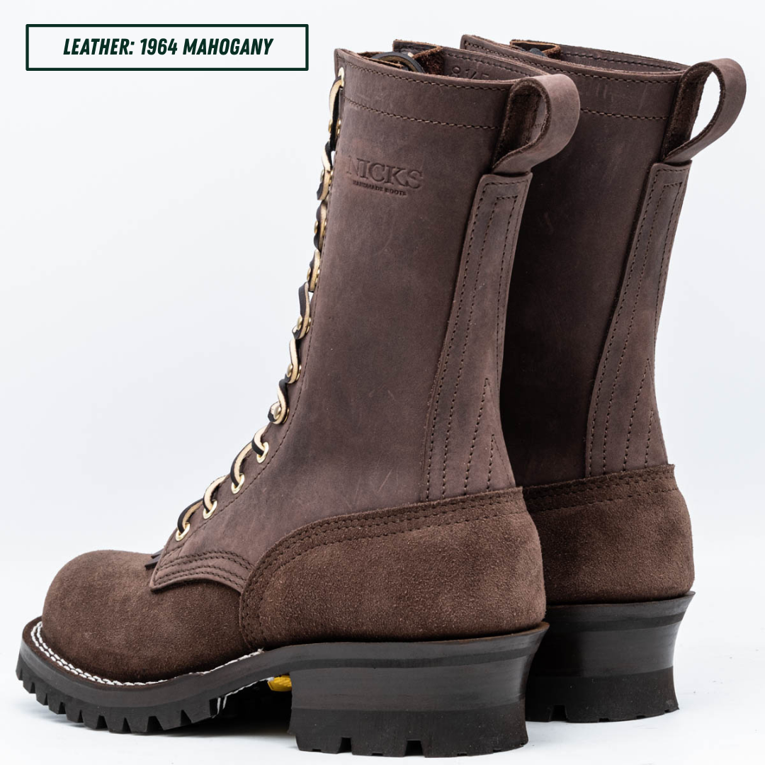 A pair of dark brown leather lace-up boots shown from the side and back on a white background, with a text label in the top-left corner reading 'LEATHER: 1964 MAHOGANY'. The boots feature a rugged black sole and a pull tab at the top.