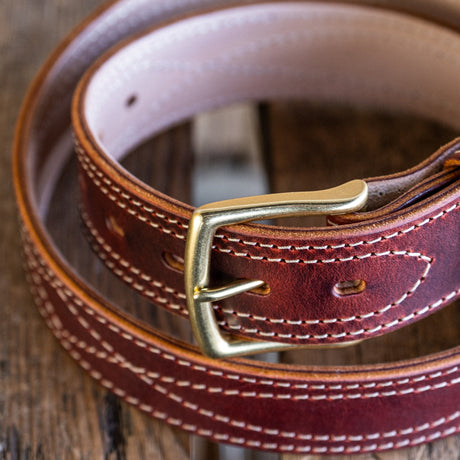 Brown leather belt with a gold buckle on a wooden surface