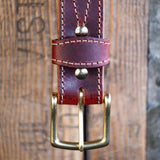Close-up of a leather belt with brass buckle on a wooden background