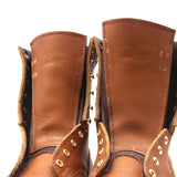 Close-up of brown leather boots with gold studs on a white background