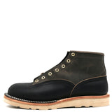 Grey and dark navy blue leather boot with brass hardware and a white wedge outsole in front of a white background.