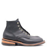 A single black leather ankle boot with gold-tone metal eyelets and a stacked black and brown sole, shown from a side profile on a white background.