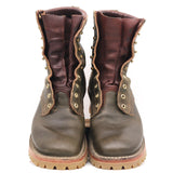 A pair of rugged lace-up ankle boots in dark green leather with reddish-burgundy leather shafts, brass-tone eyelets, and tan soles, shown against a plain white background.