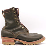 A dark olive green leather lace-up boot with brass eyelets, a brown pull tab, and a stacked lug sole with a reddish-brown midlayer and tan outsole, shown against a plain white background.