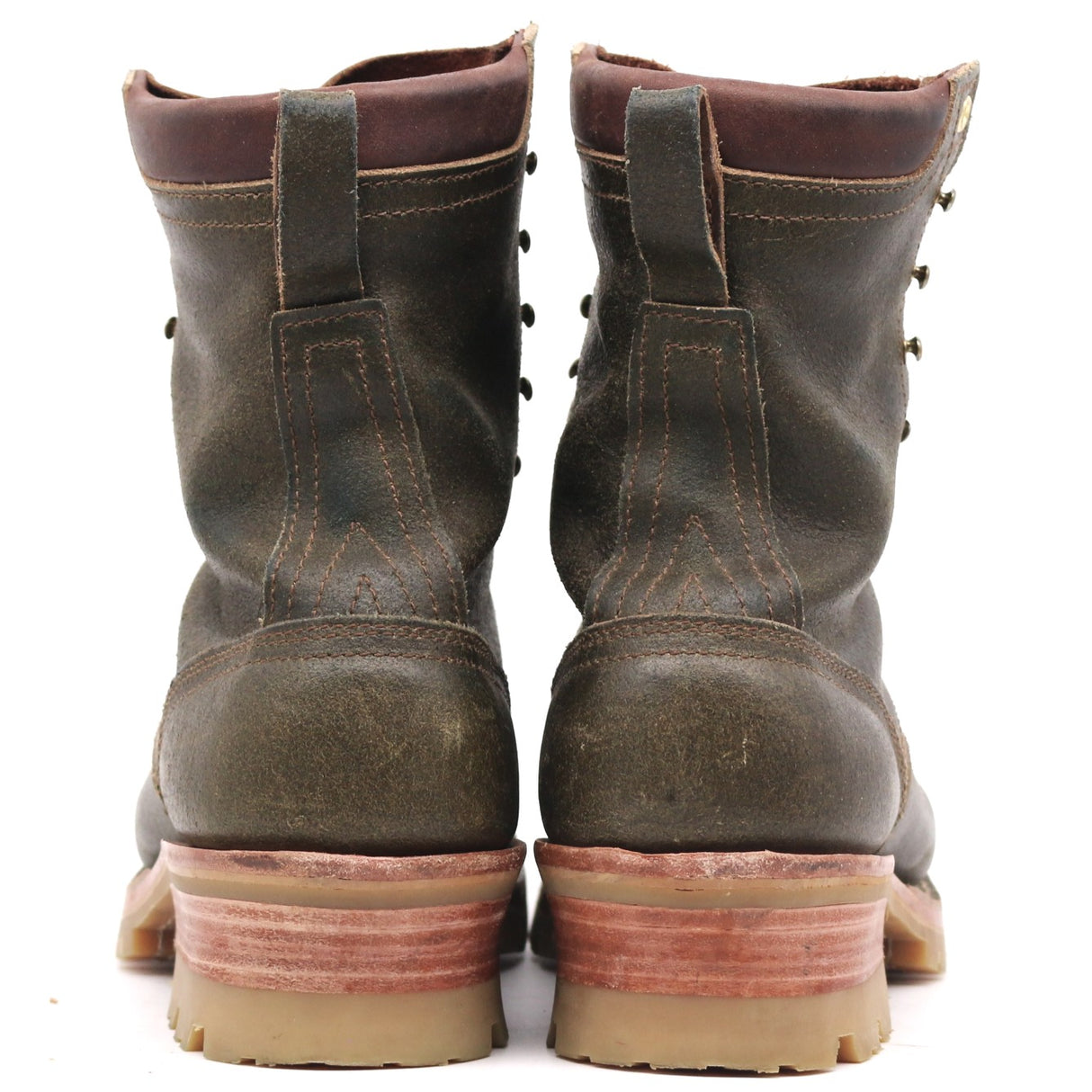 A pair of rugged dark brown leather lace-up boots shown from the back, featuring thick tan soles and reddish-brown stacked midsoles, set against a plain white background.