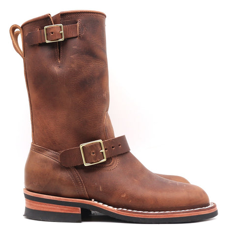 A mid-calf brown leather boot with a pull loop, a decorative strap and buckle at the ankle, and a stacked black and reddish-brown sole, shown against a plain white background.