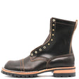 A dark brown leather lace-up ankle boot with brass eyelets, a black lug sole, and a light tan midsole layer, shown from a side profile on a white background.