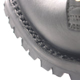 Close-up of a black leather boot corner showing the stitched welt, textured sole edge, and part of the heel on a white background.