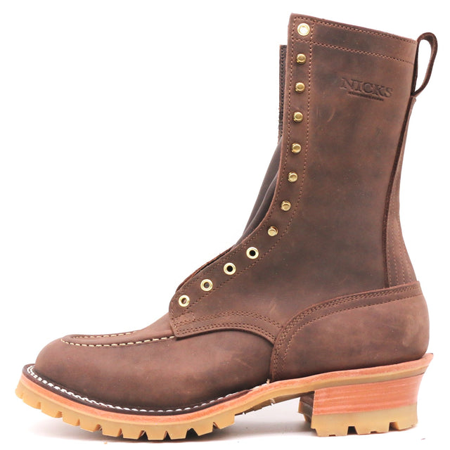 A brown leather lace-up work boot with brass eyelets, a pull tab, and a stacked tan and orange-brown sole, shown on a white background. The brand name 'NICKS' is embossed on the side.