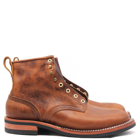 A pair of distressed brown leather ankle boots with brass eyelets and pull tabs, shown from a side profile view on a white background.