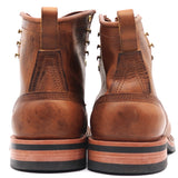 A pair of brown leather lace-up boots shown from the back, featuring pull tabs, decorative metal eyelets, and stacked soles with black and tan layers, set against a plain white background.