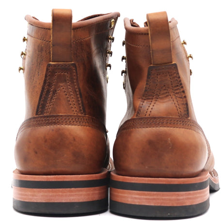 A pair of brown leather lace-up boots shown from the back, featuring pull tabs, decorative metal eyelets, and stacked soles with black and tan layers, set against a plain white background.