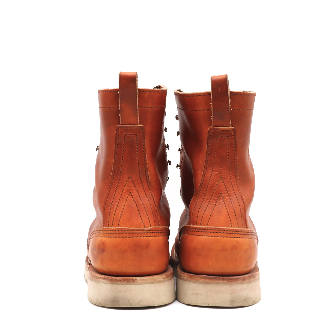 A pair of classic brown leather ankle boots shown from the back, featuring pull tabs, decorative stitching, and thick off-white rubber soles, set against a plain white background.