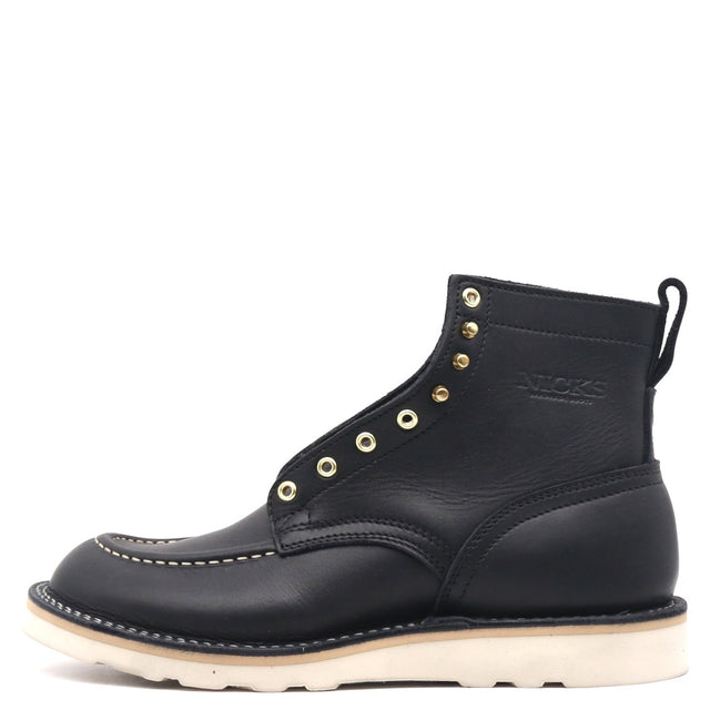 A black leather ankle boot with gold-tone metal eyelets, white contrast stitching, and a thick off-white sole, shown from a side profile on a white background.