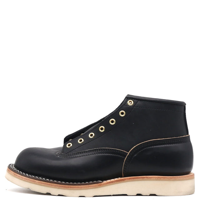 A single black leather high-top work boot with gold-tone metal eyelets, contrast stitching, and a thick off-white sole, shown from a side profile on a white background.