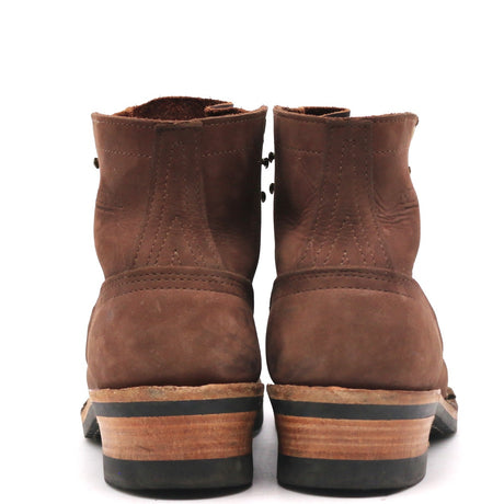 A pair of brown suede ankle boots shown from the back, featuring stacked wood-look heels with black soles, set against a plain white background.