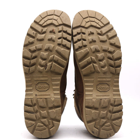 A pair of brown boots shown from the bottom, displaying their rugged treaded soles. The soles are a tan-brown color with the brand name 'Vibram' embossed in the center of each.