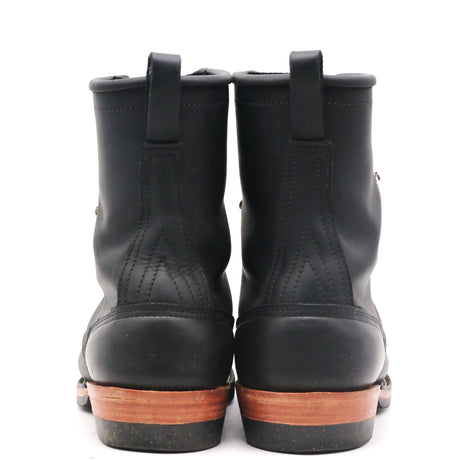 A pair of black leather work boots shown from the back, featuring pull tabs at the top and a brown wooden-look midsole.