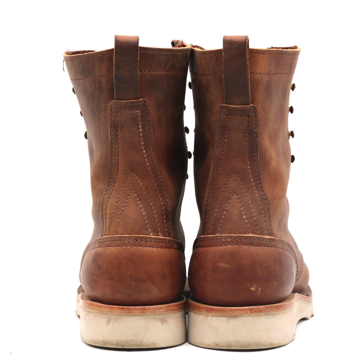 A pair of brown leather lace-up boots shown from the back, featuring a distressed finish and off-white soles, set against a plain white background.