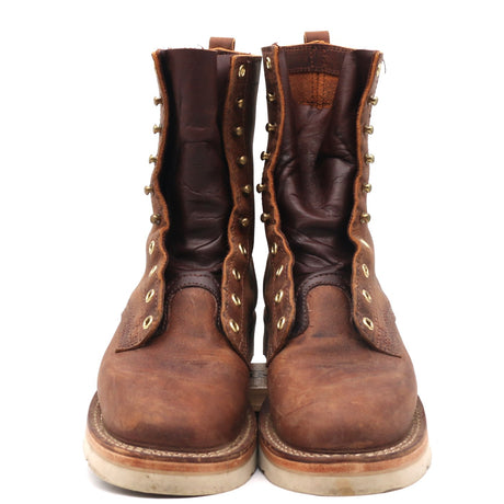 A pair of rugged brown leather lace-up boots with brass eyelets and pull tabs, shown from the front against a plain white background.