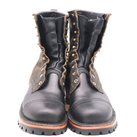 A pair of black leather lace-up boots with brown suede side panels, brass eyelets, and a rugged black sole, shown against a plain white background.